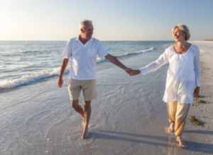 happy retired couple on beach smiling